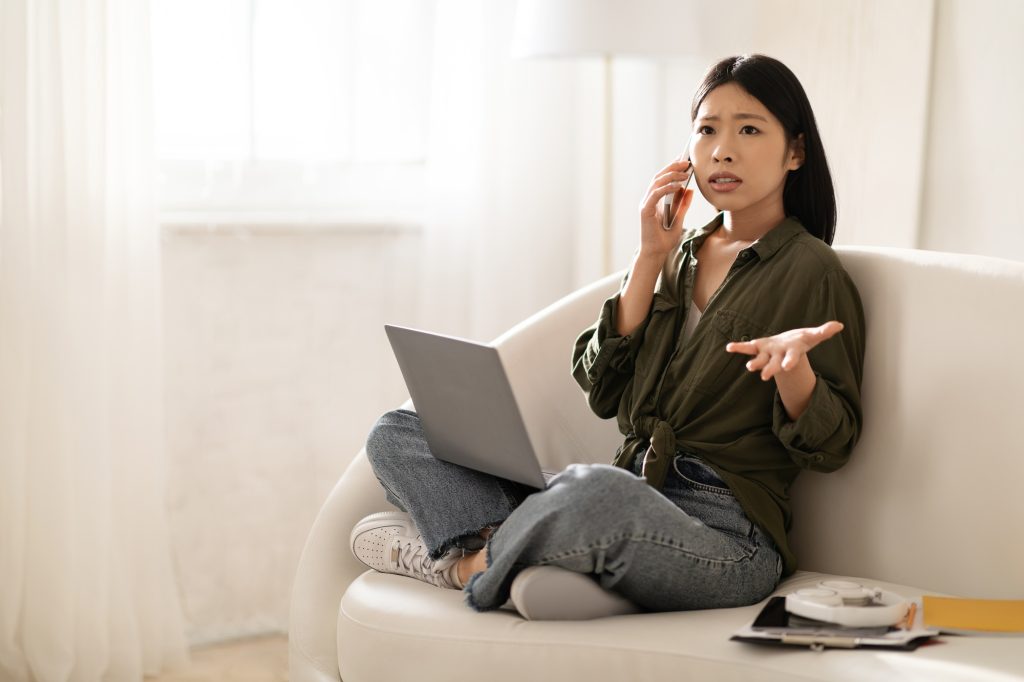 Angry asian businesswoman have phone conversation, home interior