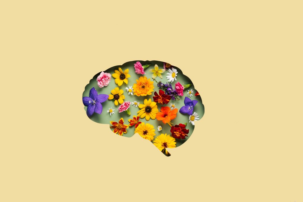 Paper cut brain symbol and flowers on yellow background